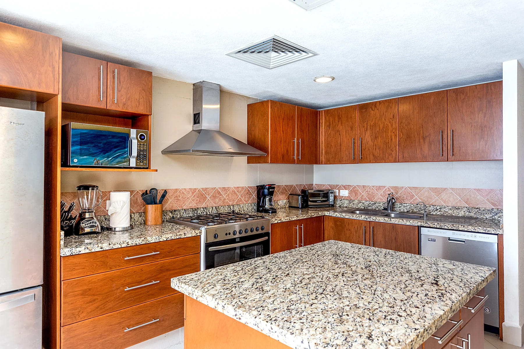 Cocina con isla de granito, madera noble y equipamiento completo