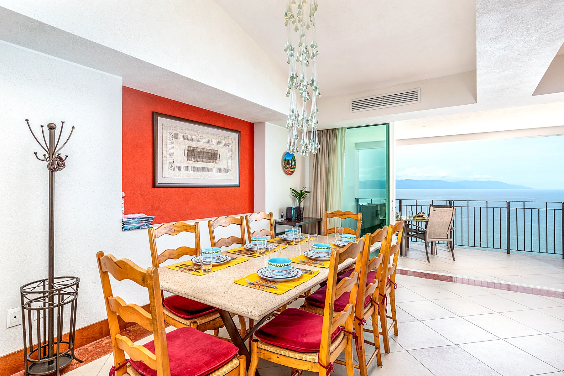 Comedor para ocho personas con la terraza abierta y el mar al fondo