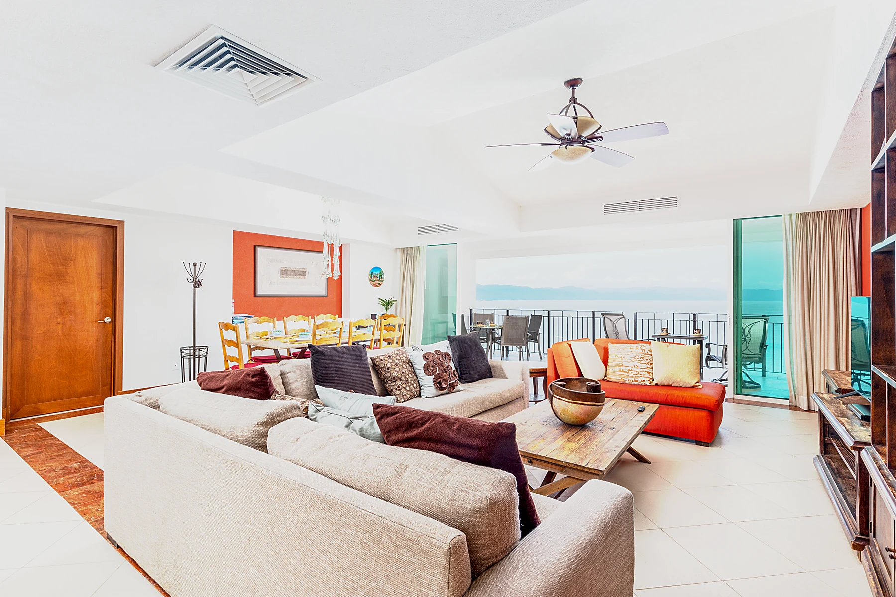Salón principal con sofás profundos y el muro de cristal abierto hacia la terraza y el mar
