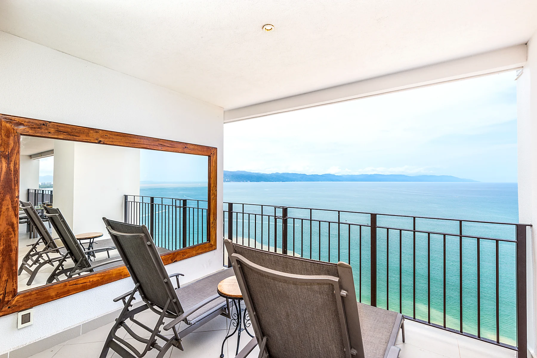 Rincón de lectura de la terraza, con espejo de madera y vista al mar